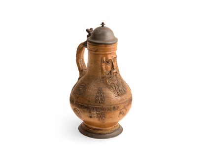 LE RAEREN

Pitcher in brown enamelled stoneware with decoration in relief of a mask...