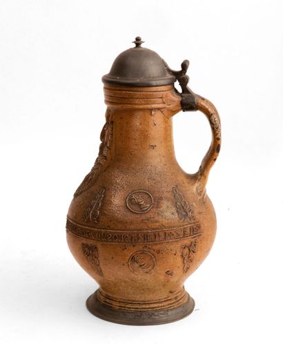 LE RAEREN

Pitcher in brown enamelled stoneware with decoration in relief of a mask...