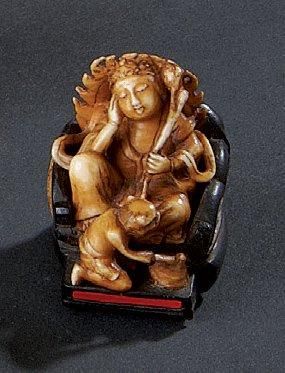 null Netsuke en ivoire et bois, Kannon assise sur son trône, un oni à ses pieds....