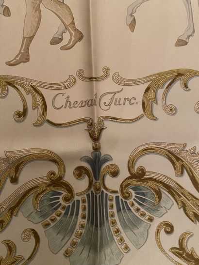 null HERMES
Carré en soie titré "Cheval turc" à fond crème, la bordure bleu ciel....