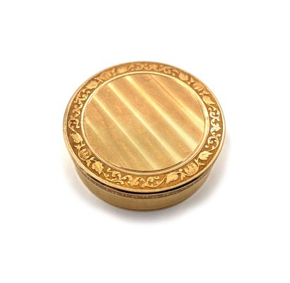 null Round box in 750 thousandths guilloché yellow gold, underlined by a frieze of...
