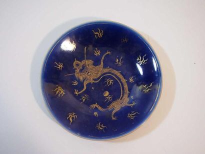 CHINE Assiette en porcelaine à fond bleu à décor en or d'un dragon. XIXe siècle....