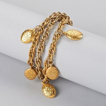 CHANEL Bracelet chaîne trois rangs en métal doré retenant des motifs ovales signés....