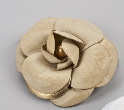 CHANEL Broche camélia en cuir ivoire et or ornée au centre d'une perle or. (Légères...