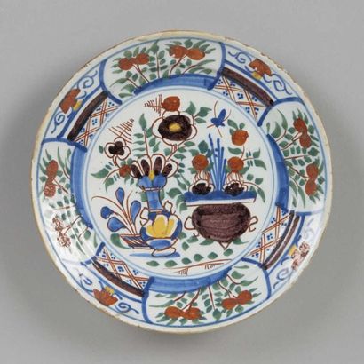 DELFT Assiette ronde à décor polychrome de vases fleuris. XVIIIème siècle. Eclats...