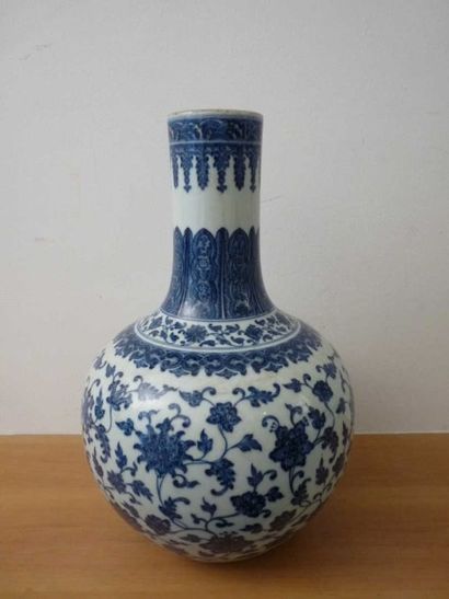 CHINE Vase bouteille en porcelaine à décor blanc bleu de feuillages et fleurs. Percé...