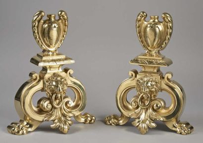 null PAIRE DE CHENETS en bronze doré à décor de têtes de lion surmontés de vases...