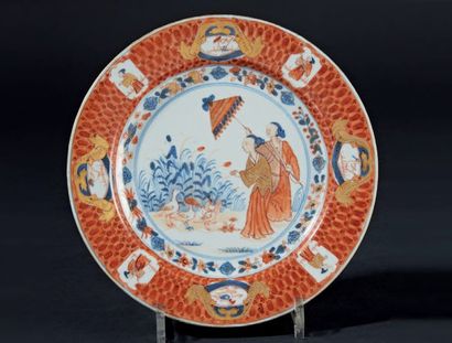CHINE Assiette en porcelaine à décor bleu, rouge et or dit Imari au Dames au parasol,...