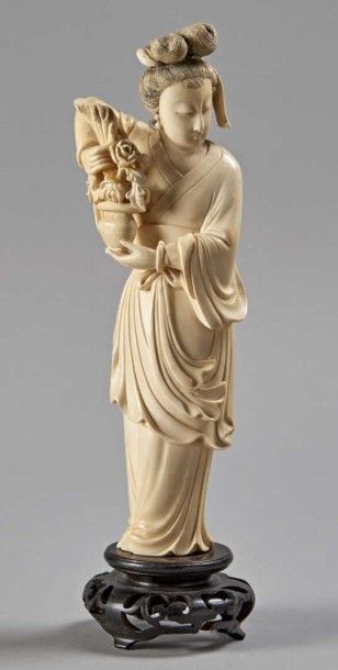 CHINE - Début XXe siècle 
Statuette de femme debout en ivoire tenant un bouquet de...
