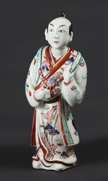 JAPON Statuette en porcelaine représentant un homme debout, sa tunique à décor bleu,...