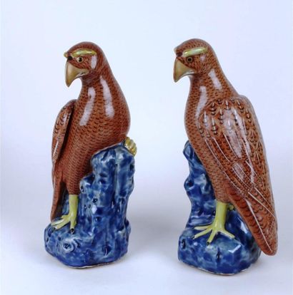 CHINE Paire de faucons en porcelaine perchés sur un rocher à fond bleu, le plumage...