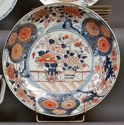 JAPON Deux plats ronds à décor bleu, rouge et or dit Imari au centre de vases fleuris...