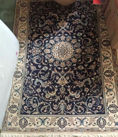 null TAPIS à fond bleu à décor de rinceaux fleuris dans une frise d'encadrement ivoire....