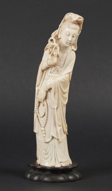 null CHINE - Début XXe siècle
Statuette de Guanyin en ivoire, debout, tenant un rosaire...