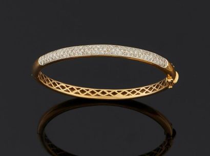 null Bracelet rigide ouvrant en or jaune 750°/oo, orné au centre d'un pavage de diamants...
