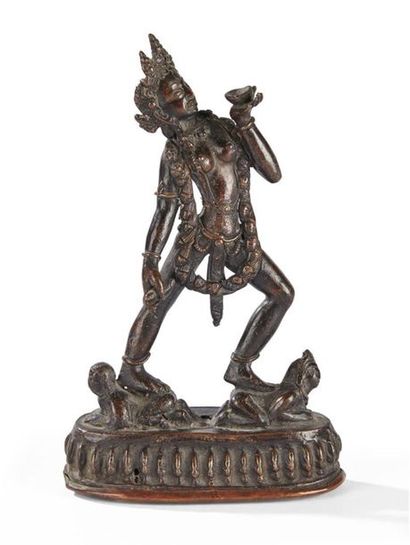 null TIBET - Vers 1900
Statuette en bronze à patine brune de dakini tenant le kapala...