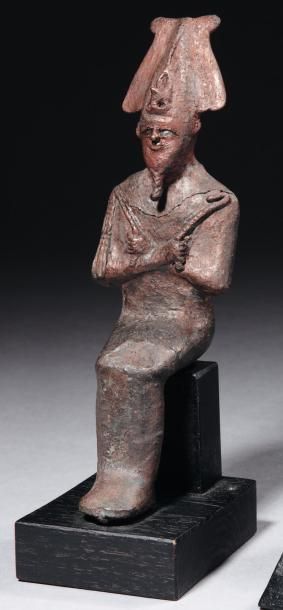 Égypte Statuette votive représentant le dieu Osiris. Il est assis, les mains émergeant...