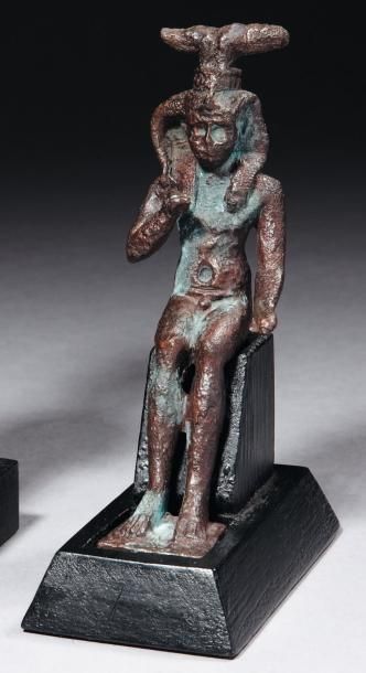 Égypte Statuette votive représentant le dieu Somtous. L'enfant-dieu est nu, assis,...
