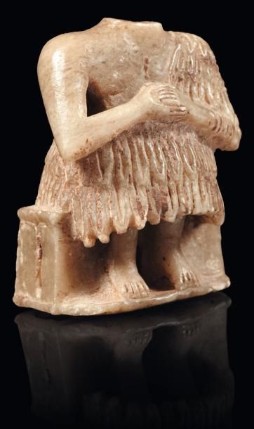 Orient Orant au kaunakès. Statuette votive acéphale représentant un homme assis sur...