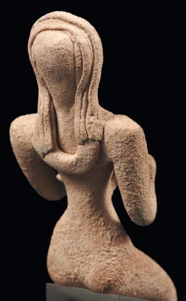Orient Maternité. Statuette représentant une femme nue, assise, tenant contre sa...