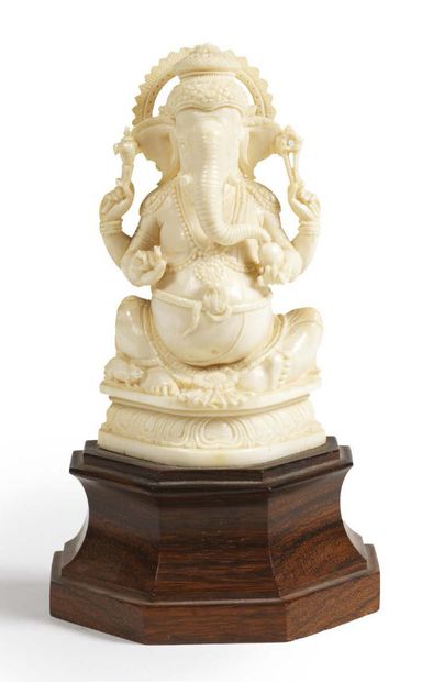 null STATUETTE DE GANESH ASSIS sur un socle en forme de lotus à quatre bras, tenant...