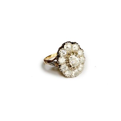 null An 18K (750) yellow gold daisy ring set with a central old-cut diamond weighing...