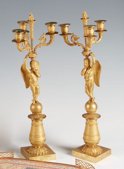 null Coppia di candelabri a tre fiamme in bronzo dorato, i bracci sostenuti da figure...