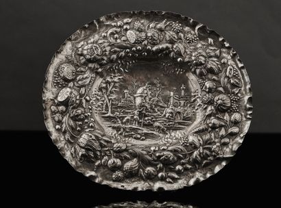 A silver dish with an embossed and engraved...