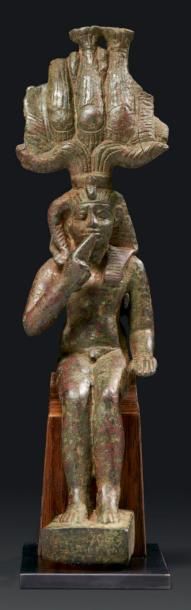 ÉGYPTE STATUETTE VOTIVE DU DIEU SOMTOUS. Le jeune dieu est nu, assis, le bras gauche...