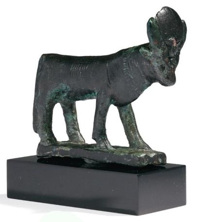 ÉGYPTE STATUETTE VOTIVE DU TAUREAU APIS. Il est passant sur une base, la tête sommée...