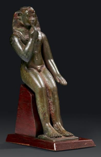 ÉGYPTE STATUETTE VOTIVE D'UN DIEU-ENFANT. Il est nu, assis, le bras gauche le long...