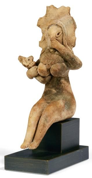 ORIENT MATERNITÉ. Statuette représentant une femme nue, assise, tenant contre elle...