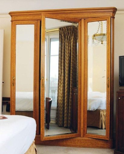  Grande armoire en bois clair ouvrant à trois portes miroir. H_227 cm L_182 cm P...