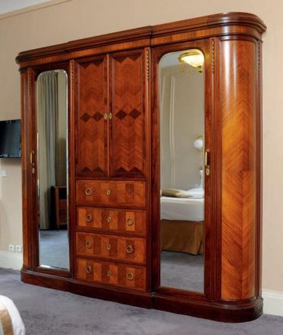 null Grande armoire dressing en bois de placage reposant sur une plinte. Elle ouvre...