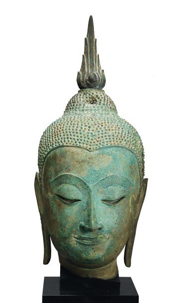 null Tête de bouddha en bronze à patine verte. Les oreilles lobées et allongées....