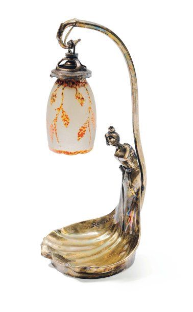 null Rousseau Lampe en bronze argenté à décor d'une femme à la robe, formant coquille....