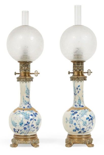 DIFFLOTH 
PAIRE DE LAMPES à pétrole en porcelaine à décor en bleu de feuillages.
Monture...