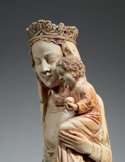  VIERGE À L'ENFANT en ivoire sculpté en ronde-bosse. Base circulaire à décor de deux...
