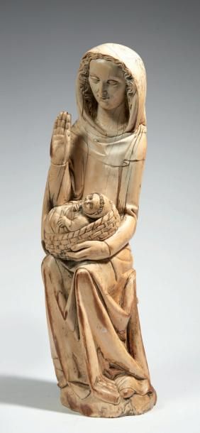  VIERGE À L'ENFANT en ivoire sculpté en ronde-bosse. Assise, Marie porte son Fils...