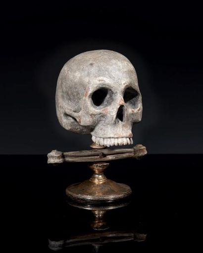 null Crâne en terre cuite et bois polychromé monté sur un socle portant un os avec...