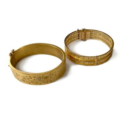 null Suite de deux bracelets joncs plats ouvrant en métal doré, l'un ajouré, l'autre...