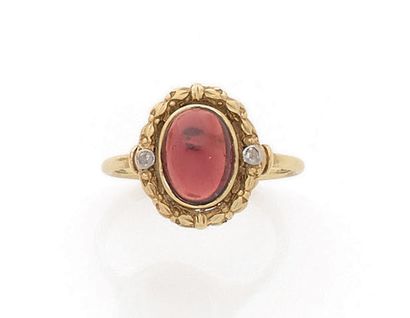 null BAGUE en or jaune 18K (750), ornée d'un grenat cabochon entouré d'une guirlande...