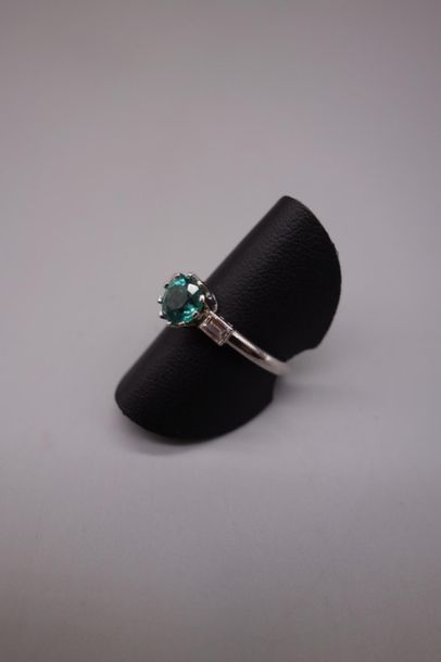 null Bague en or gris 18K (750/oo) centrée d'une émeraude ronde épaulée par deux...