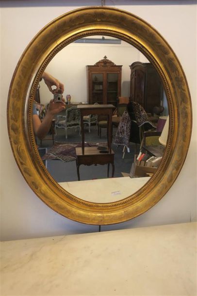 Miroir ovale en bois sculpté doré à décor...