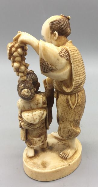 null Okimono en ivoire et rehauts bruns, représentant un paysan et ses deux enfants,...