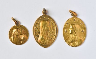  Lot in 18K yellow gold (750/oo) comprising three religious medals: a round one of...