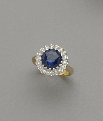 A two-tone 18K (750/oo) gold ring centered...