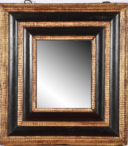 null Mirror with inverted profile, in blackened and gilded wood, framed with wavy...