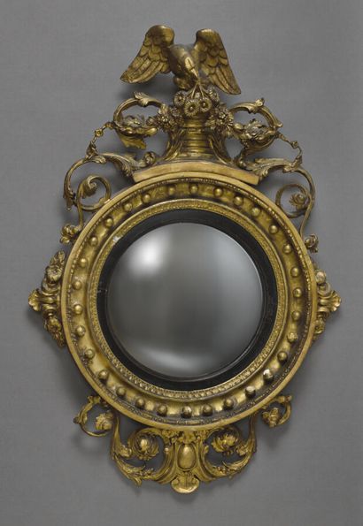 null Witch mirror with circular view in wood and gilded stucco, topped by an eagle...