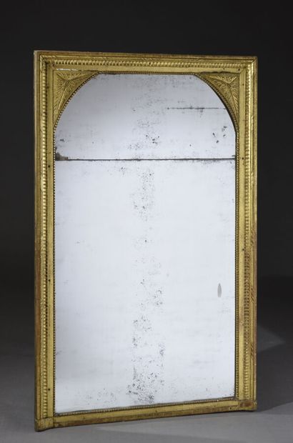null Gilded wood mirror, frame carved with a braid, channels and pearls, upper spandrels...